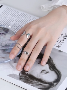 Close-up of minimalist silver rings set including wide band and heart open ring