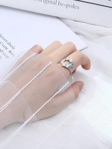 Detailed close-up of a silver minimalist lava textured ring worn on a model finger