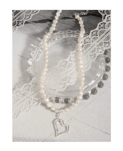Detailed macro of baroque pearl necklace featuring a silver hollow heart pendant accessory