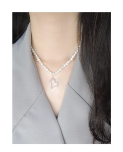 Detail of silver irregular hollow heart pendant and natural freshwater pearls on model