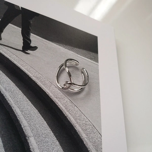 Macro shot of silver minimalist crisscross ring on modern fashion magazine page