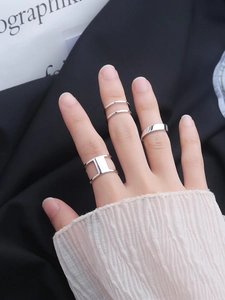 Close-up of minimalist S925 sterling silver layered rings set worn on female fingers
