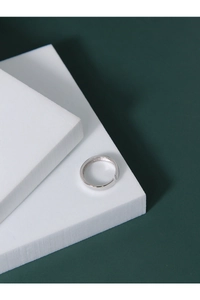 Close-up of a minimalist silver open ring with a polished surface on a geometric pedestal