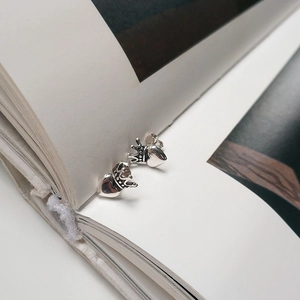 Macro detail of S925 sterling silver crown heart stud earrings on a book page