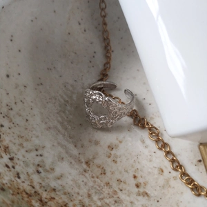 Close-up of S925 sterling silver lava ring with irregular texture on a golden chain