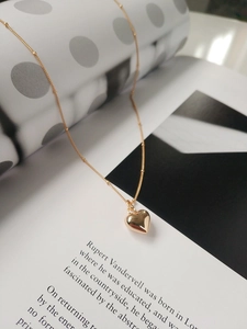 Dettaglio ravvicinato del ciondolo a cuore 3D dorato su una collana a catena fine