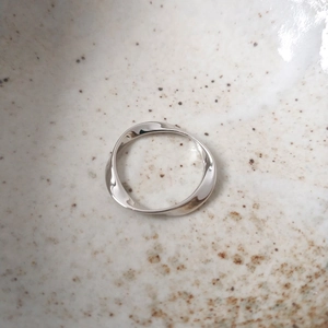 Macro shot of S925 sterling silver Mobius ring with twisted design in a ceramic bowl