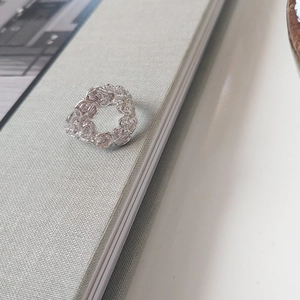 Artistic detail of silver lava ring with irregular textures on a grey fabric background