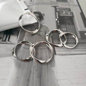 Detail view of five-piece silver Mobius twist ring set on minimalist magazine background