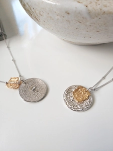 Détail macro de pendentifs pièces lave bicolores avec texture martelée et chaîne fine