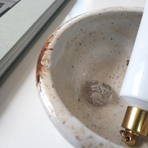Detailed view of silver lava texture ring placed in minimalist ceramic aesthetic setting