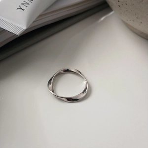 Macro shot of S925 sterling silver Mobius ring with interior hallmark on a white surface