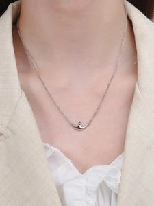 Macro shot of silver crown pendant necklace worn on neck for a minimalist fashion look
