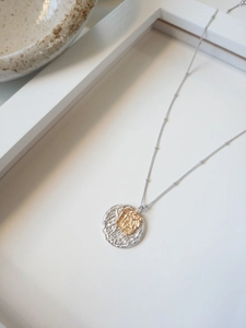 Détail du pendentif effet lave argenté avec touche dorée sur une chaîne satellite chic