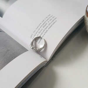 Detail of silver lava ring with irregular texture placed on a minimalist magazine page