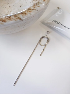 Detail shot of a minimalist S925 sterling silver box chain drop earring on white surface