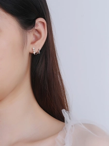 Detail of S925 silver stud earrings with graduated white pearls on a female model