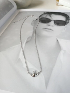 Polished silver crown pendant necklace on a fashion magazine background
