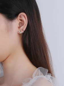 Close-up of S925 sterling silver streamline earrings with white pearls on a model