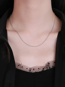 Close-up of minimalist S925 sterling silver chain necklace on model with dark background