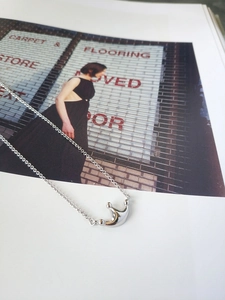 Macro shot of S925 sterling silver minimalist crown necklace on editorial magazine