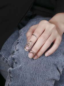 Detail eines silbernen Nagelring-Sets mit geometrischem Hohlbuchstabendesign am Finger