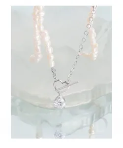 Detail of S925 silver heart TO toggle necklace with pearl and drop zircon on glass