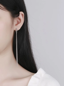 Detail of long S925 sterling silver chain tassel earrings worn by a model in a close-up