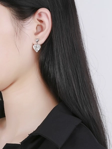 Detailed view of silver heart earrings featuring an embossed angel Cupid on the pendant