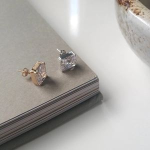 Nahaufnahme quadratischer Zirkonia-Ohrstecker in Gold und Silber mit Vier-Krallen-Fassung