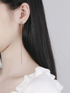 Close-up of long silver chain tassel earrings with twisted knot detail on a model