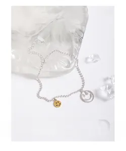 Détail de la chaîne en argent S925 avec sourire évidé en argent et breloque smiley doré plein