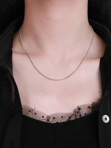 Close-up of minimalist S925 sterling silver curb chain worn on neck with black outfit