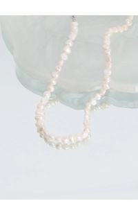 Close-up of elegant baroque pearl necklace with silver clasp on glass texture