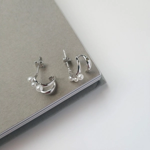 Close-up of S925 sterling silver pearl earrings with a streamlined double arc design