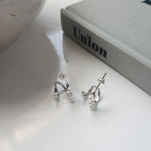 Detail of silver S925 earrings with three gradient pearls on curved metal brackets