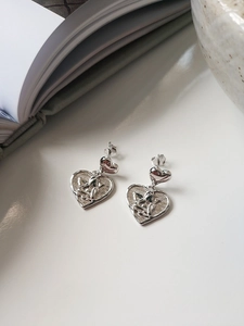 Detailed close-up of silver heart earrings featuring intricate angel relief and textured finish