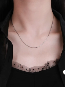 Close-up of a delicate S925 sterling silver box chain necklace on a model wearing black
