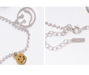 Détail du bracelet de cheville en argent S925 montrant les breloques souriantes et le poinçon