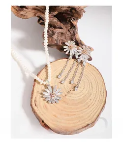 Detail of silver daisy pendant pearl necklace with matching long tassel earrings on wood