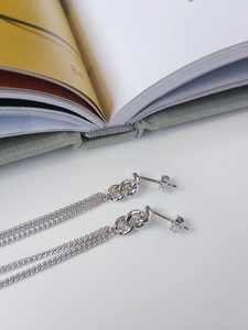 Detail of S925 sterling silver long chain tassel earrings with polished metal finish