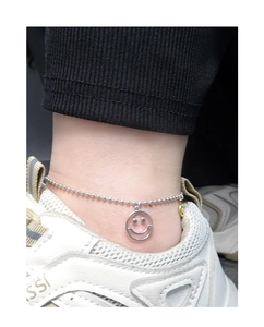 Détail d'une chevillère en argent S925 avec breloque smiley portée à la cheville