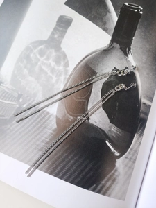 Detailed view of long S925 sterling silver chain tassel earrings on artistic magazine background