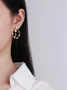 Detail of gold celestial hoop earring with moon, sun, and stars worn on ear