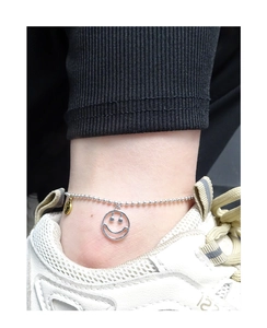 Gros plan d'une chevillère en argent S925 avec un pendentif smiley ajouré sur la cheville