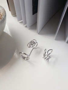 Detail eines geometrischen S925 Silber Doppelrings und Wellenrings auf weißem Buch