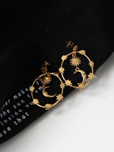 Macro shot of vintage gold sun and crescent moon earrings with engraved celestial faces