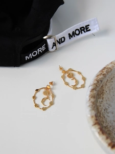 Detailed view of vintage gold celestial earrings with moon and star design on white surface
