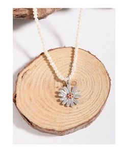 Macro shot of silver daisy pendant with orange gems on a natural pearl bead necklace