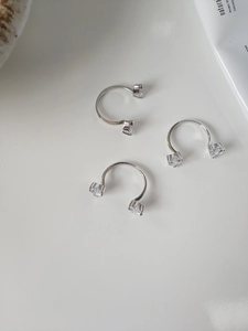 Close-up of three minimalist silver open rings with sparkling zircon stones